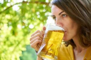Woman enjoying a glass of cold beer outdoors on a sunny day
