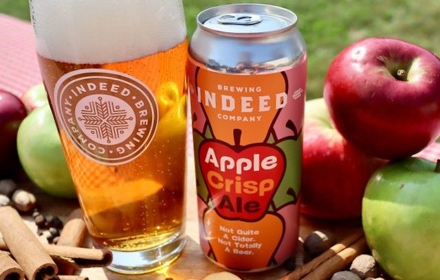 Indeed Brewing Company Apple Crisp Ale can and glass with apples, cinnamon, and spices, highlighting its crisp, fall-inspired flavor