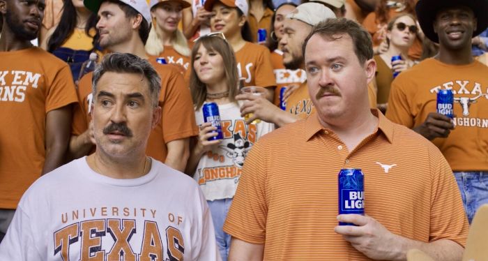 Comedian Shane Gillis and John McKeever in Texas Longhorns fan gear at a college football game, drinking Bud Light during their "Vendor Voices" ad campaign