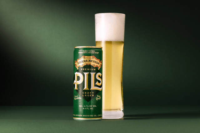 Sierra Nevada Premium PILS can next to a full glass of beer with foam head on a dark green background