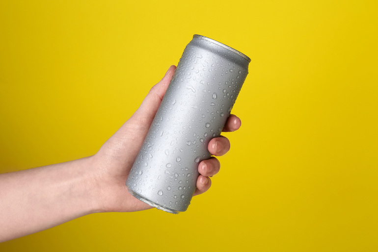 A hand holding a cold, silver non-alcoholic canned drink