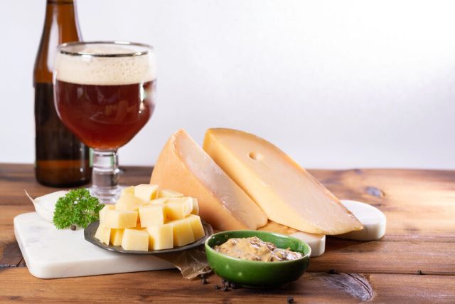 A selection of gourmet cheeses paired with a glass of craft beer on a wooden table