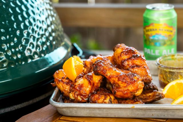 grilled chicken wings on table with pale ale in the background