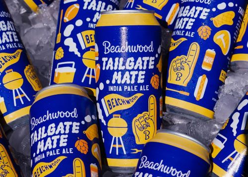 A close-up shot of several vibrant blue cans of "Beachwood Tailgate Mate India Pale Ale" chilling in a bed of ice, with condensation visible on the cold cans
