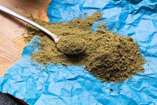 A spoonful of Red Dragon Kratom powder on blue parchment paper