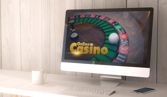 Kajot Casino online roulette game on a desktop screen with a mobile phone and a coffee cup on the desk