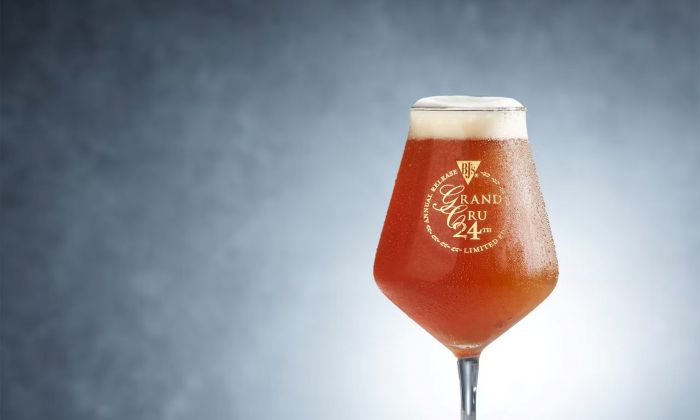 A close-up shot of a glass of BJ's Grand Cru beer with a creamy head and condensation on the glass.
