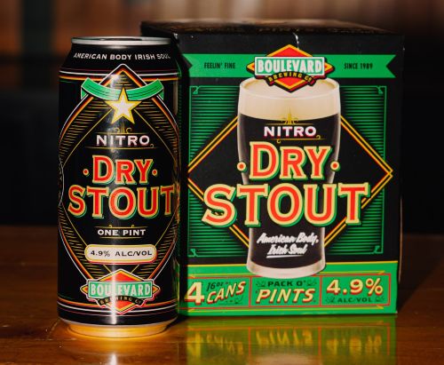 A single can of Boulevard Brewing Co. Nitro Dry Stout is shown next to a four-pack box of the same beer. The can and box are black with green and yellow accents. The box shows an image of a glass of the stout with a creamy head