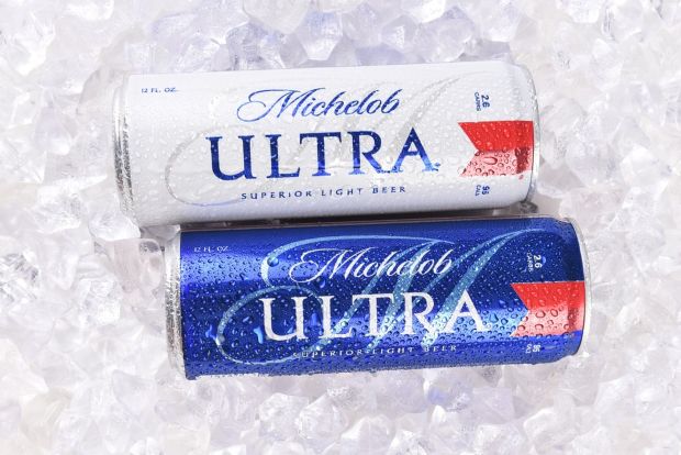 "Two cold Michelob Ultra beer cans, one white and one blue, with condensation on a bed of ice."