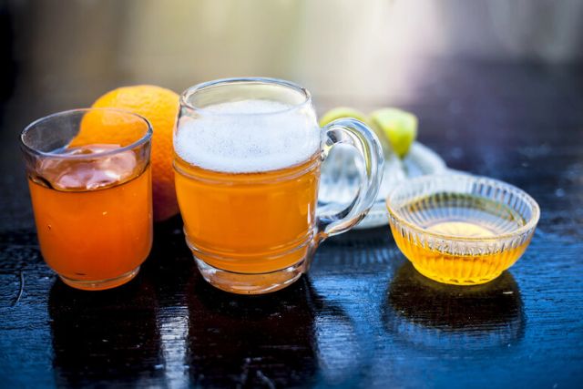  A variety of non-alcoholic beverages, including herbal tea, citrus drinks, and honey on a dark wooden table