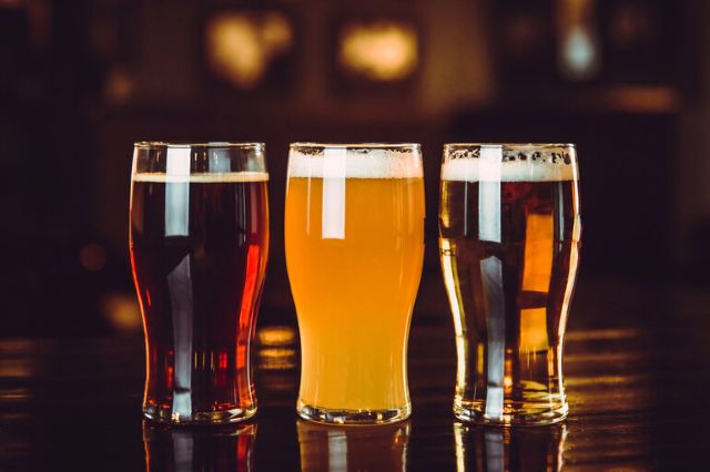 Three pints of craft beer in different colors sitting on a bar counter at a casino