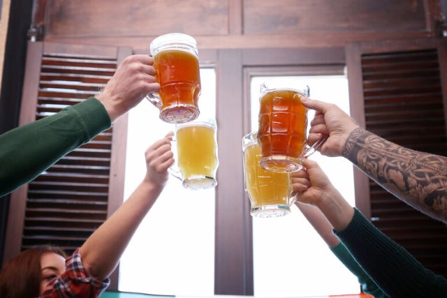 Friends toasting mugs of craft beer while celebrating sports and American brewing culture