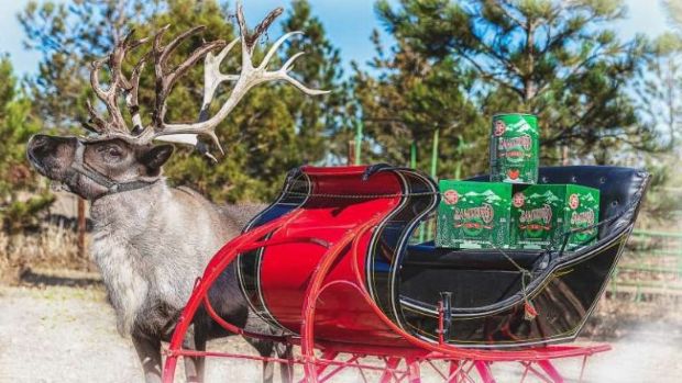 A reindeer pulling a red and black sleigh loaded with cases and cans of Breckenridge Christmas Ale