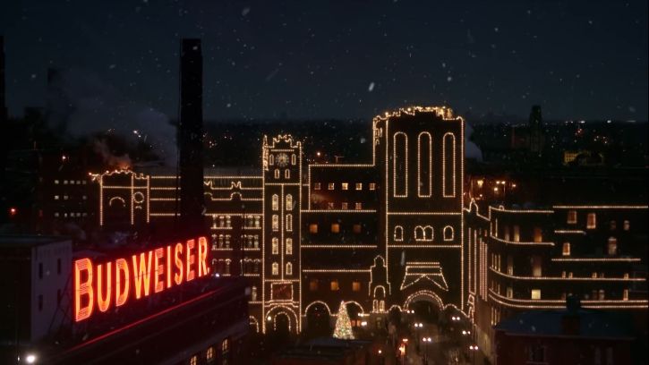 Anheuser-Busch Brewery in St. Louis, Missouri, adorned with Christmas lights at night as snow falls.