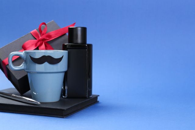 Alt Text: Elegant corporate gift set with a mug, notebook, pen, cologne bottle, and ribbon-wrapped box on a blue background.