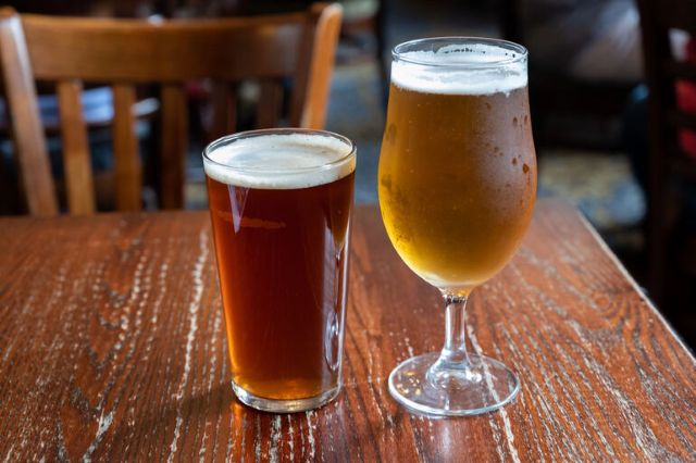 Two beers on a wooden table in a taproom