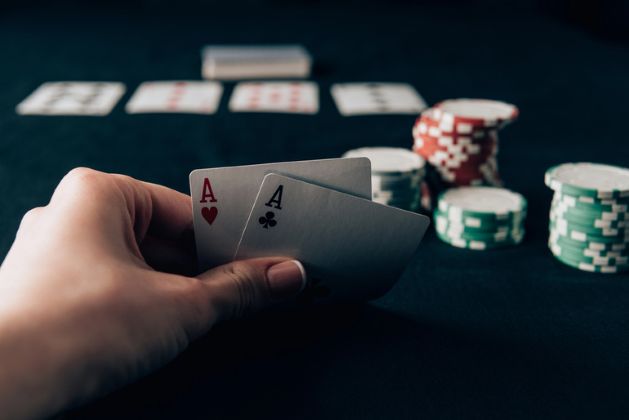 Player holding pocket aces at a poker table with chips and cards during a game at Velobet Casino Australia.