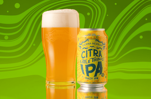 A pint glass of hazy orange beer and a yellow can of Sierra Nevada Citra Little Thing Hazy IPA on a reflective surface with a green wavy background.