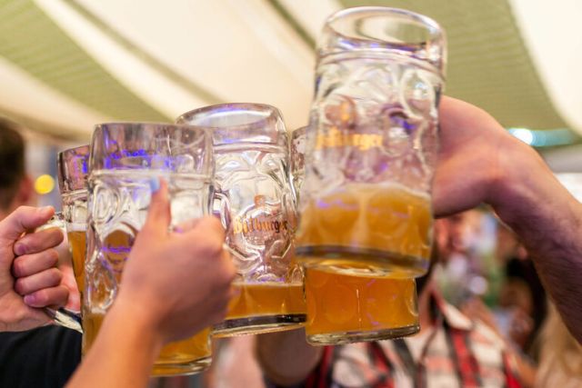 Group of people clinking large beer steins at a crowded beer festival