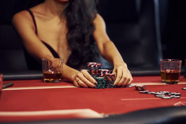 A poker player stacking chips at a casino table with craft beer drinks beside them, representing top poker venues with craft beer in the United States..
