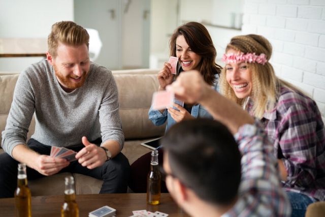 Friends enjoying a casual card game while drinking craft beer on a relaxed weekend.
