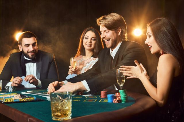 Group of well-dressed people enjoying drinks while playing at a sweepstakes-style casino table, suggesting a safe and fun gaming environment.
