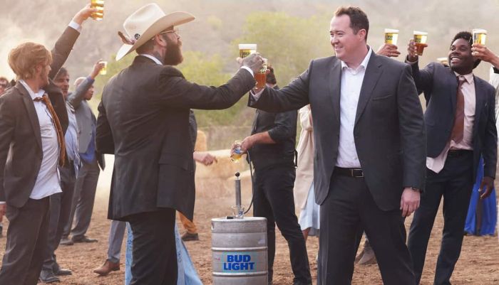 Post Malone (left, in cowboy hat) and Shane Gillis (right, in suit) filming the 2026 Bud Light Super Bowl commercial, titled "Keg". The scene is set at a wedding where a runaway keg causes the entire party to tumble down a