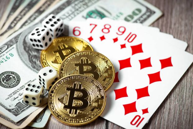 A stack of Bitcoin and a set of dice on playing cards.