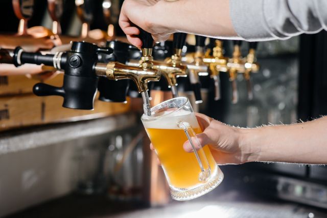 A bartender filling a mug of NA beer from the bar counter in the pub.