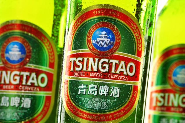 Close-up of three Tsingtao beer bottles with focus on the main green and red labe