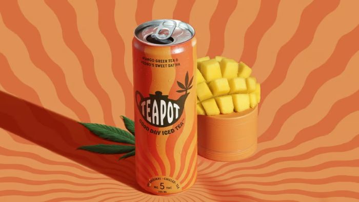  A can of Teapot Good Day Iced Tea (Mango Green Tea, 5mg THC Sativa), a cut mango half in a stand, and cannabis leaves, set against an orange background.