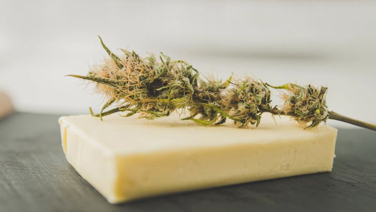 Cannabis flower placed on butter for cannabutter infusion preparation