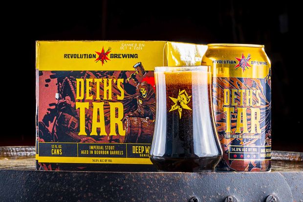 A box, can, and glass of Revolution Brewing Deth's Tar imperial stout aged in bourbon barrels, set on a wooden surface.