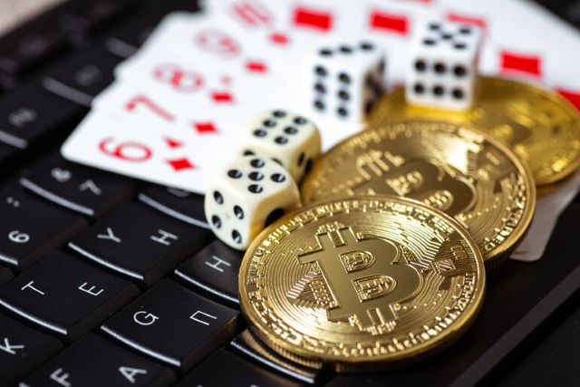 Bitcoin coins and casino dice on keyboard showing crypto casino gameplay.