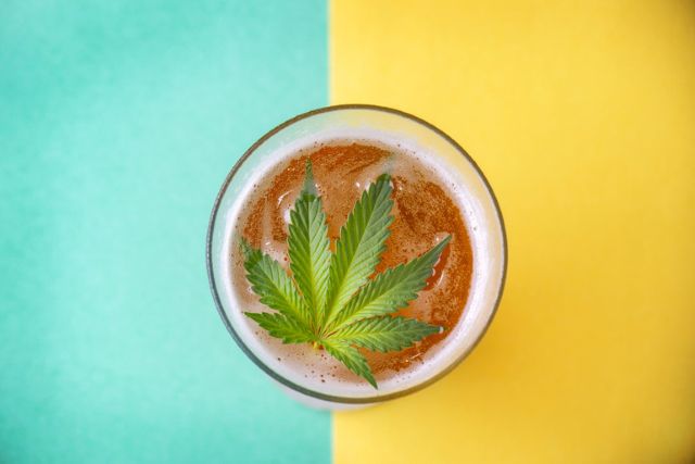 Top-down view of a frothy alcoholic drink topped with a cannabis leaf.