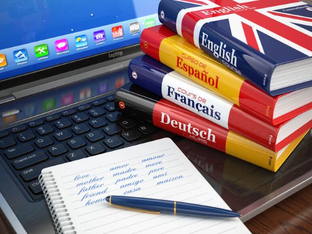 Language learning books and a notebook beside a laptop, representing adult language learning after 30.