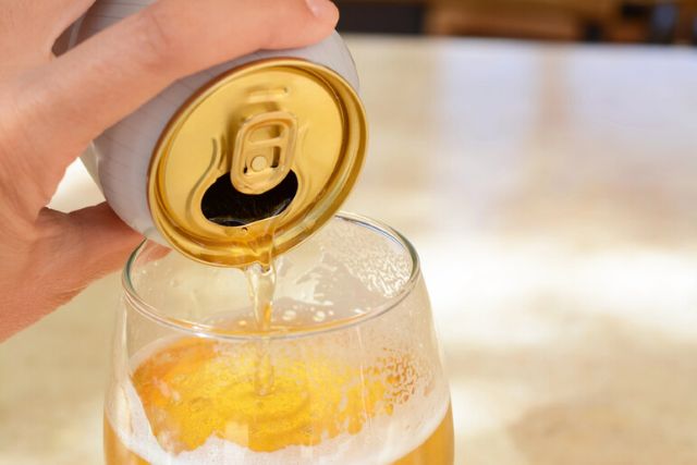 Beer being poured from a can into a glass.