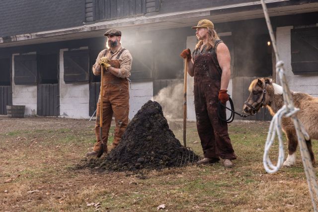Two men and a miniature horse shoveling manure outside a barn. The image is from a Super Bowl 2026 commercial for Garage Beer called "The Brotherly Shovel" and features former Philadelphia Eagles players Jason Kelce and Beau Alle