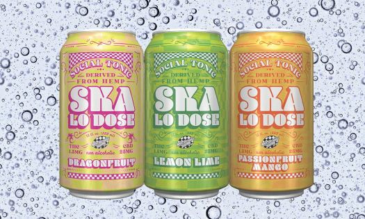 Three cans of Ska Lo Dose Social Tonic, featuring Dragonfruit, Lemon Lime, and Passionfruit Mango flavors, shown against a background of bubbles.