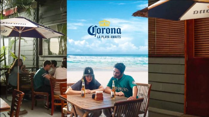 A promotional image for Corona beer featuring a three-panel layout. The central panel shows a man in a Mariners jersey and a woman in a baseball cap sitting at an outdoor wooden table with two beers, set against a bright beach background with the text "Corona: LA PLAYA AWAITS." The side panels show people dining at an outdoor patio under large Corona-branded umbrella.