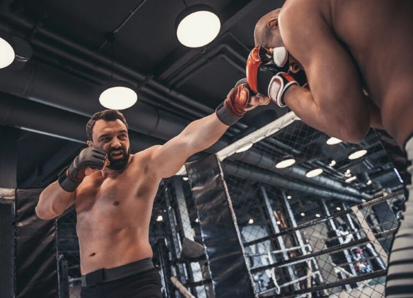 Two MMA fighters sparring in a cage, capturing the intensity of a live UFC broadcast in a Canadian sports bar setting.