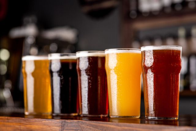 : A lineup of assorted craft beers in different colors and styles displayed on a bar counter, representing the variety and challenges within Florida’s craft beer market.
