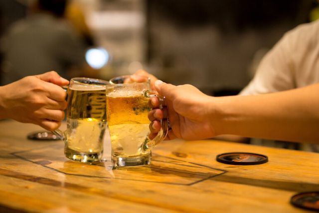 Two hands clinking glasses of beer in a cheers moment, representing why Pinoy beer is loved by foreigners and the Filipino drinking culture.