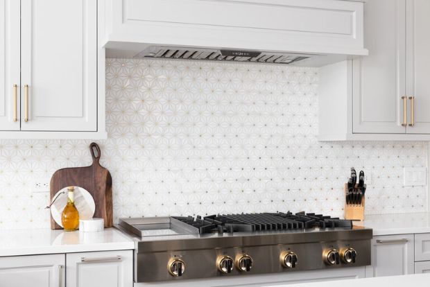 Modern kitchen with geometric tile backsplash and stainless steel stove, designed for stylish beer pairing spaces.