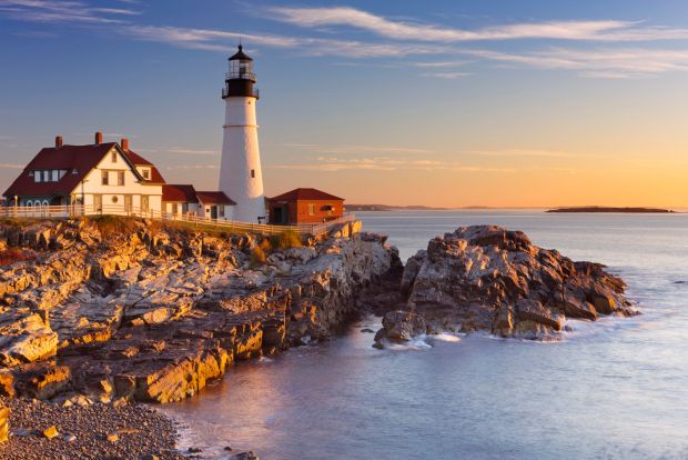 Portland Head Light and keeper's house on a rocky coast at sunset.