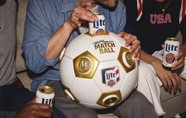 A group of friends sitting together, holding Miller Lite cans, while one person holds a soccer ball-shaped cooler filled with cans.