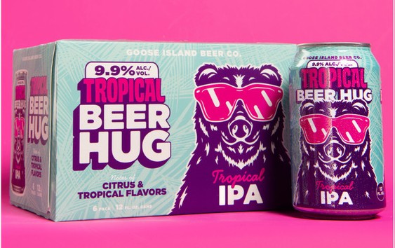 A 6-pack box and a single can of Goose Island Tropical Beer Hug Imperial IPA, featuring a purple bear graphic wearing pink sunglasses against a bright pink background.