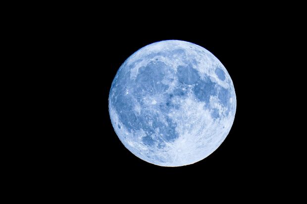 A full moon with a distinct light blue tint against a solid black background.