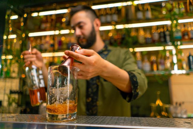 Bartender preparing a canned-style cocktail at a bar, illustrating the growing popularity of ready-to-drink cocktails alongside craft beer. 