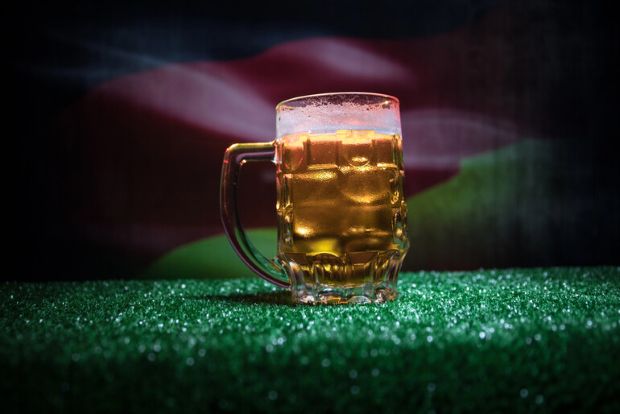 Golden beer mug on a football pitch, representing the beer traditions of World Cup nations.